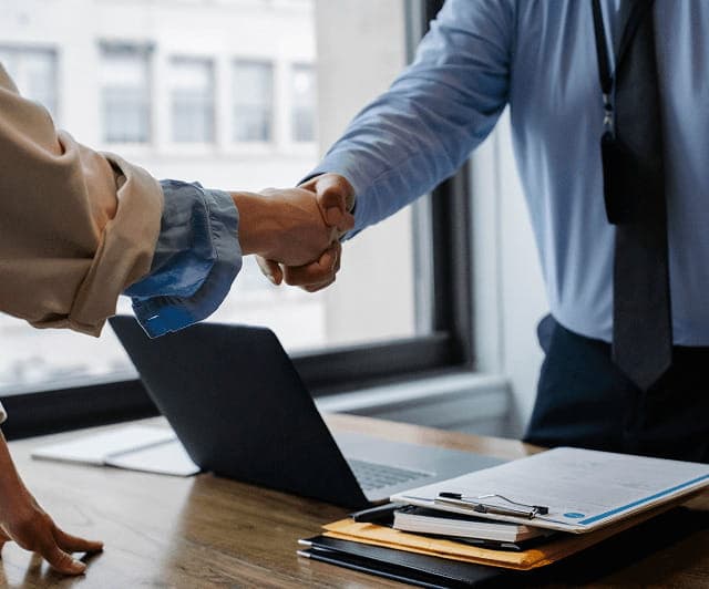 Profesionales estrechando las manos junto a un proyecto